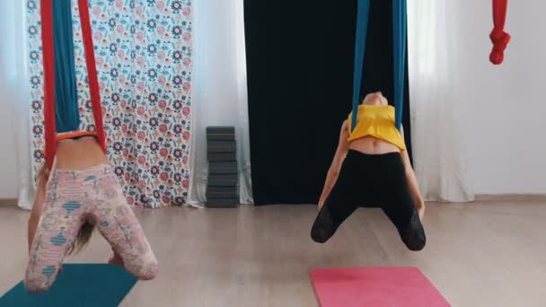 Yoga udara - dua wanita yang sedang berlatih - berayun di tempat tidur gantung bersandar di belakang — Stok Video