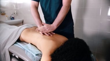 Kayropraktik tedavi - doktor hastaya masaj yapıyor - elleriyle sırtına bastırıyor.