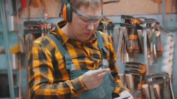 Timmerwerk binnen - een man houtbewerker trekt een potlood en het maken van markeringen op het houten detail — Stockvideo