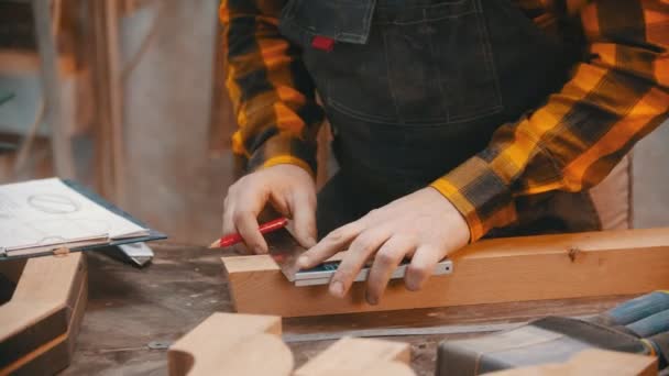 Carpintaria dentro de casa - um homem marceneiro fazendo marcas para cortar o detalhe de madeira com um lápis e um medidor — Vídeo de Stock