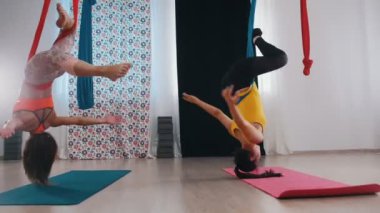 Hava yogası - eğitim alan iki kadın - baş aşağı asılı ve etrafında dönüyorlar - eğleniyorlar