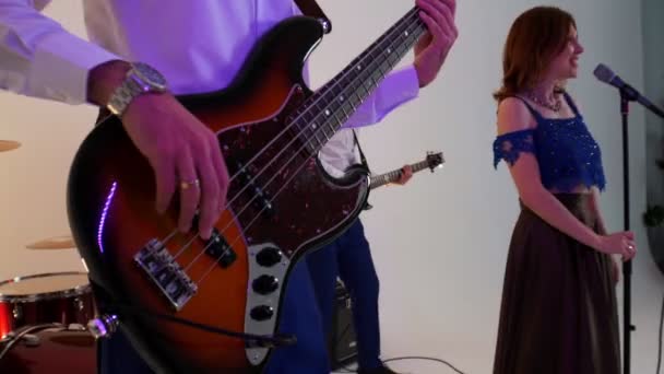 Ett musikband med fyra personer som spelar sång i neonbelysning - män i vita skjortor och en kvinna i klänning — Stockvideo