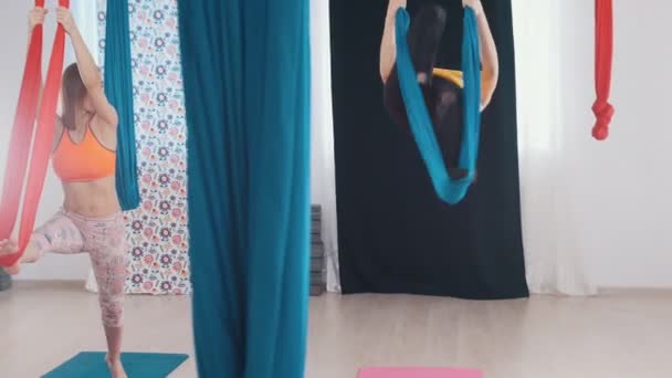 Hava yogası - iki kadın antrenman yapıyor - tek bacakla hamağa çıkıyorlar. — Stok video