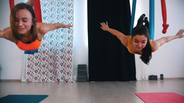 Aerial Yoga - zwei Frauen liegen in Hängematten auf dem Bauch und schwingen darin — Stockvideo