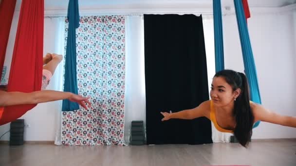 Воздушная йога в студии - две женщины лежат в гамаках на животах и качаются в них — стоковое видео
