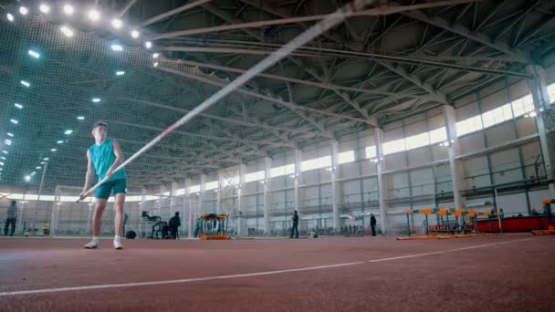 Pole vaulting - sportman stijgt een lange paal en loopt — Stockvideo