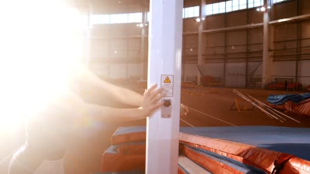 Salto de poste - mujer joven está girando la grúa y levantando la barra — Vídeos de Stock