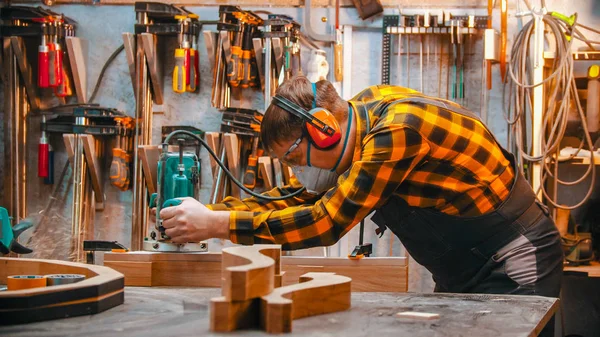 Carpintería interior - un carpintero hombre pule el detalle de madera con un esfuerzo en el taller —  Fotos de Stock