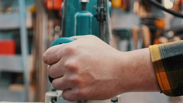 Zimmerei drinnen - ein Holzarbeiter poliert das Holzdetail von oben in der Werkstatt - hält die Poliermaschine in der Hand — Stockfoto