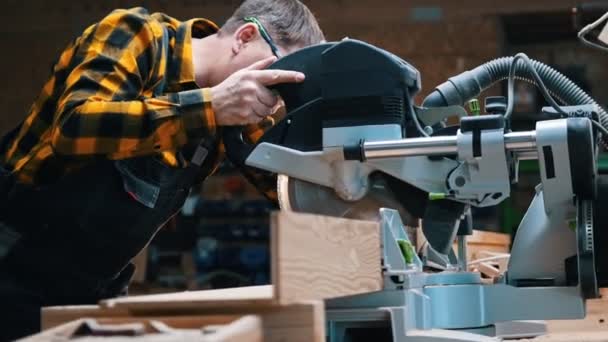 Βιομηχανία ξυλουργικής - ένας ξυλουργός που κόβει ένα κομμάτι ξύλο με ένα μεγάλο δισκοπρίονο σε ένα εργαστήριο — Αρχείο Βίντεο