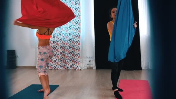 Luchtyoga - Twee vrouwen verspreiden het kleed van een rode en blauwe hangmatten voor yoga — Stockvideo