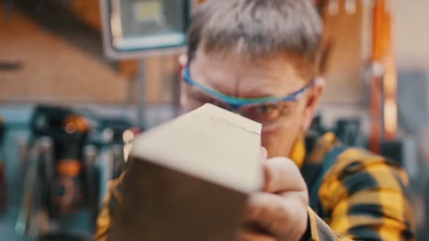 Industria de carpintería - trabajando en el taller - un carpintero hombre inspeccionar detalle de madera para las imperfecciones — Vídeo de stock