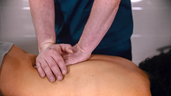 Kiropraktisk behandling - läkaren som ger patienten massage - trycker mjukt ner på nedre delen av ryggen med händerna — Stockfoto