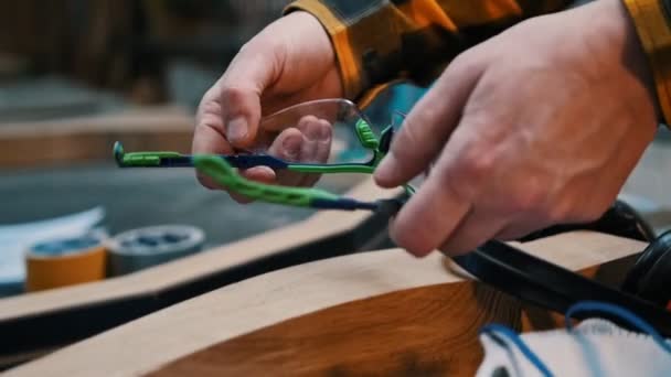Carpintaria em casa - um homem marceneiro colocar em um óculos de proteção — Vídeo de Stock