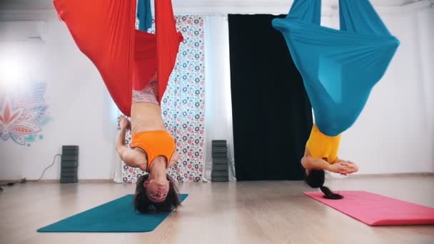 Повітряна йога дві жінки висять у гамаку догори ногами — стокове відео