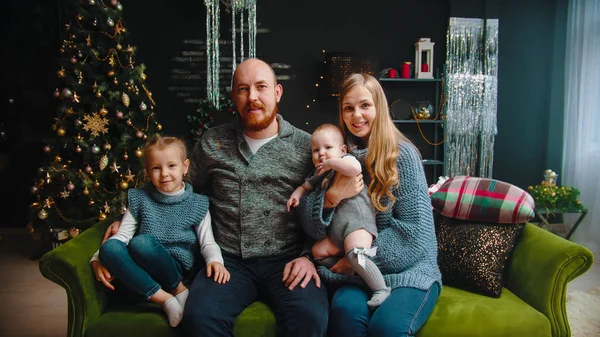 Концепция Рождества - семья Хэппу сидит на диване и смотрит в камеру — стоковое фото