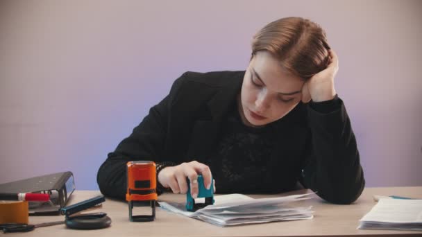 Office - tired girl is putting two stamps on documents and throwing them away — Stockvideo