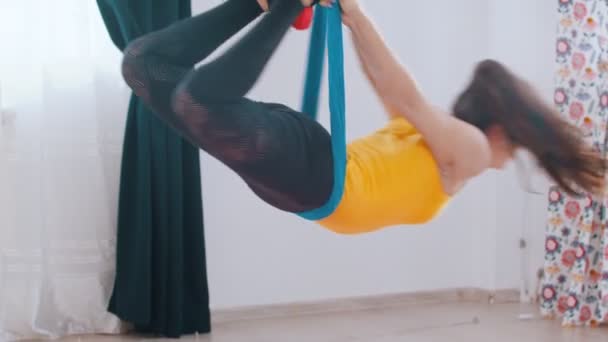 Yoga yapmak için hamakta asılı duran ve kendi etrafında dönen genç bir kadın. — Stok video