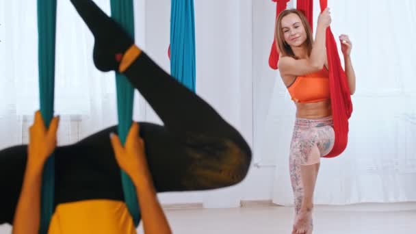 Dos mujeres que tienen un entrenamiento de aero yoga en el estudio - una mujer atlética mirando a su entrenador con admiración — Vídeo de stock