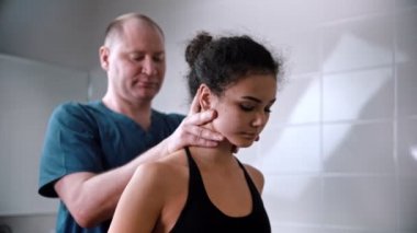 Kayropraktik tedavisi. Doktor seanstan önce genç bayanı muayene ediyor.