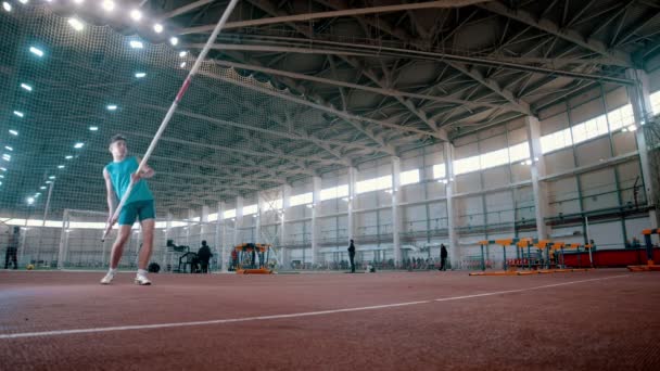 Pole vaulting - atleet in blauw t shirt stijgt een lange paal en gaat lopen — Stockvideo