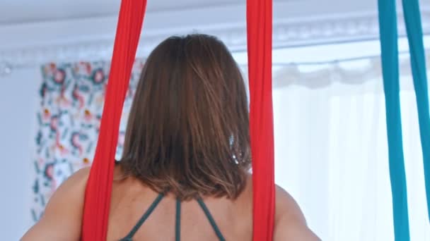 Воздушная йога - женщина висит в гамаке для йоги — стоковое видео