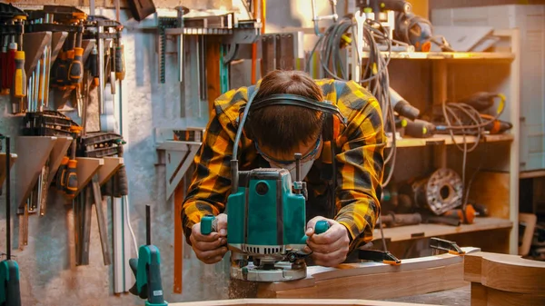 Carpintería interior: un carpintero hombre pule la plancha en el taller —  Fotos de Stock