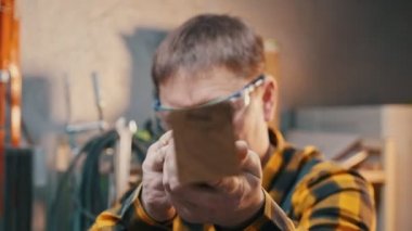 Marangozluk endüstrisi - atölyede çalışan - bir marangoz kusurları için ahşap detaylarını denetler