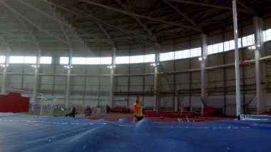 Sırıkla atlama - sarı tişörtlü sporcu koşuyor ve barın üzerinden atlıyor