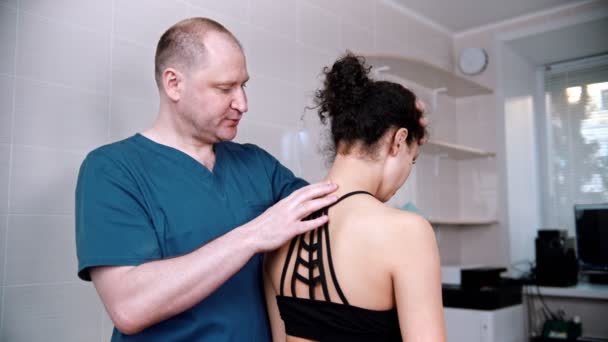 Chiropractische behandeling - de arts inspecteert de jonge vrouw voor de sessie - buigt de nek op en neer en naar de zijkanten — Stockvideo