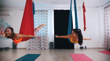 Hava yogası - iki kadın hamaklarda karnının üstünde yatar ve sallanır - birbirlerine bakarlar.
