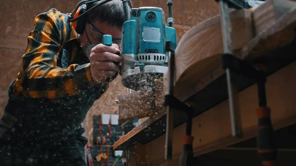 Menuiserie intérieure - un menuisier polit les détails en bois dans l'atelier - poussière tombant du détail — Photo