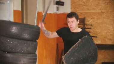 Spor salonunda bir erkek şövalye, bir grup lastik üzerinde antrenman yapıyor.