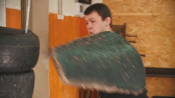 Ein Mann Ritter mit einem Tätowierungstraining in der Turnhalle mit dem Schwert - Training auf dem Reifenstapel — Stockvideo