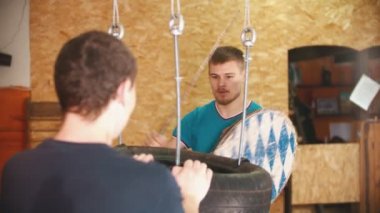 Spor salonunda kılıçlarla antrenman yapan bir şövalye. Paketi tutan başka bir adam.