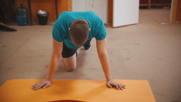 Een man in een blauw t-shirt doet oefeningen op zijn benen — Stockvideo