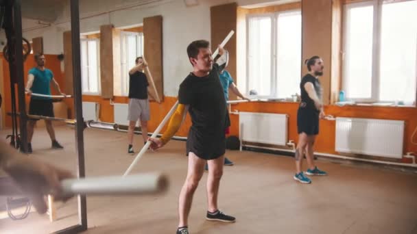 Hombres entrenando con el travesaño en el pequeño gimnasio — Vídeo de stock