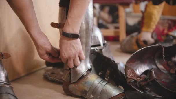 Un homme revêtu d'une armure pour l'entraînement au combat des chevaliers - mettre une protection sur les mollets — Video