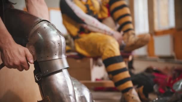 A man putting on an armour on the knee for the knights battle training — Stock Video