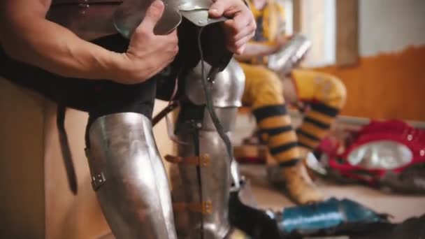 Un hombre poniéndose una armadura en la rodilla para la batalla de los caballeros — Vídeo de stock