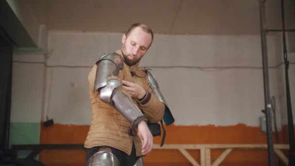 Een man die een ridderharnas aantrekt - hij trekt een volledig harnas aan voor de training — Stockvideo