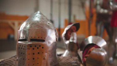 Erkekler soyunma odasında zırh giyiyorlar. Bir adam diğerine yardım ediyor.