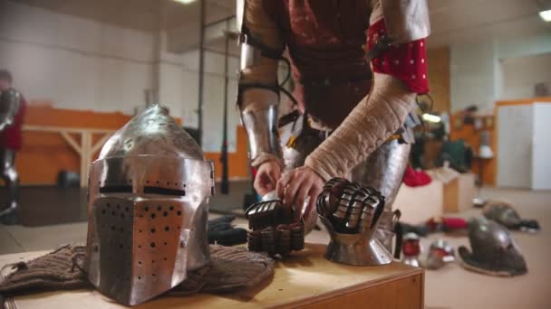 Een man in de kleedkamer doet de ijzeren handschoenen aan. — Stockvideo