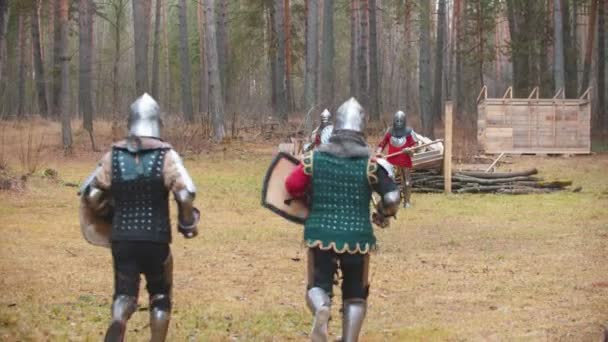 Fyra män riddare som har en träning kamp på fältet i mitten av skogen - springa mot varandra och starta en kamp — Stockvideo