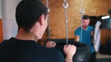 Şövalyeler antrenman yapıyor. Kılıç dövüşü becerilerini lastikler üzerinde çalıştıran bir adam. Paketi tutan başka bir adam.