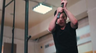 Spor eğitimi, dövmeli bir adam spor salonunda büyük bir tekere çekiçle vuruyor.