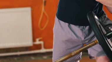 Spor eğitimi - bir adam ellerini büyük bir halterle eğitiyor - halteri sağa sola hareket ettiriyor.