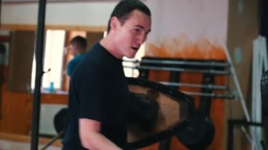 Şövalyeler antrenman yapıyor. Terli bir adam, tahta bir kalkan tutan lastikler üzerinde kılıç kullanma becerisini geliştiriyor.