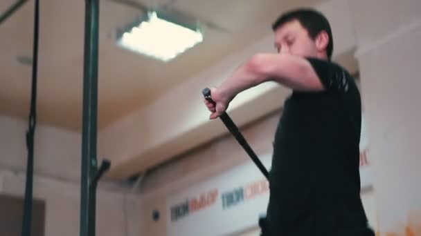 Αθλητική προπόνηση - ένας αθλητικός άνδρας με τατουάζ χτυπάει ένα μεγάλο λάστιχο με ένα μεταλλικό σφυρί στο γυμναστήριο — Αρχείο Βίντεο