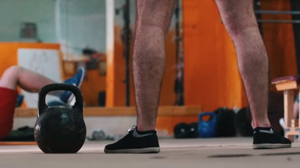 Sportieve training - mannen in de sportschool doen oefeningen - een man op de voorgrond zet een gewicht neer — Stockvideo